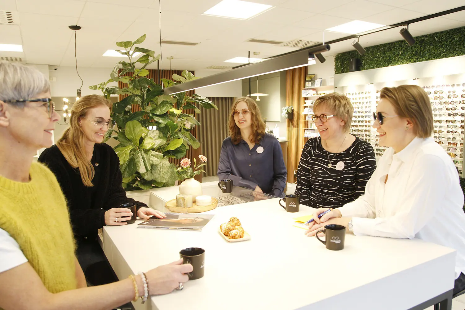 Personalen på Jacobssons Optik sitter runt ett bord och fikar.